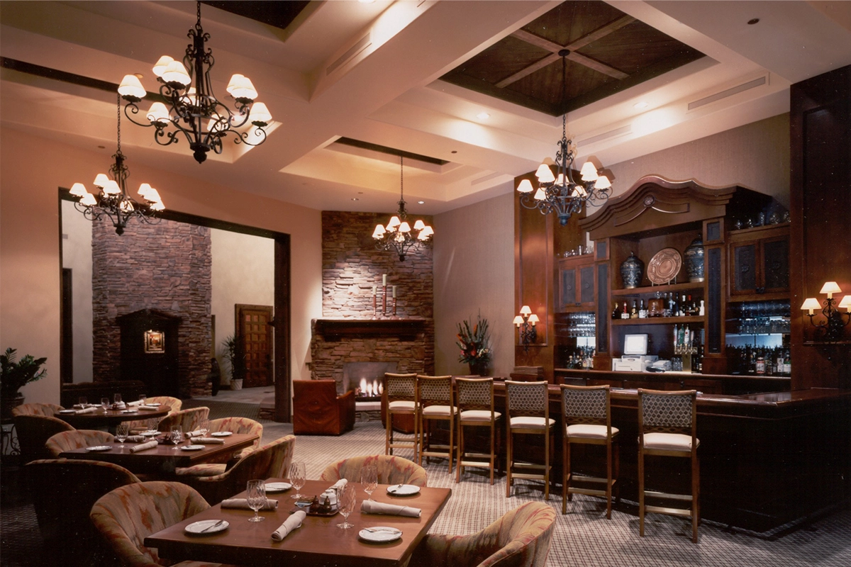 Fire Rock Country Club elegant bar and dining room with wrought iron chandeliers, stone fireplace, and wooden bar featuring desert-inspired interior design
