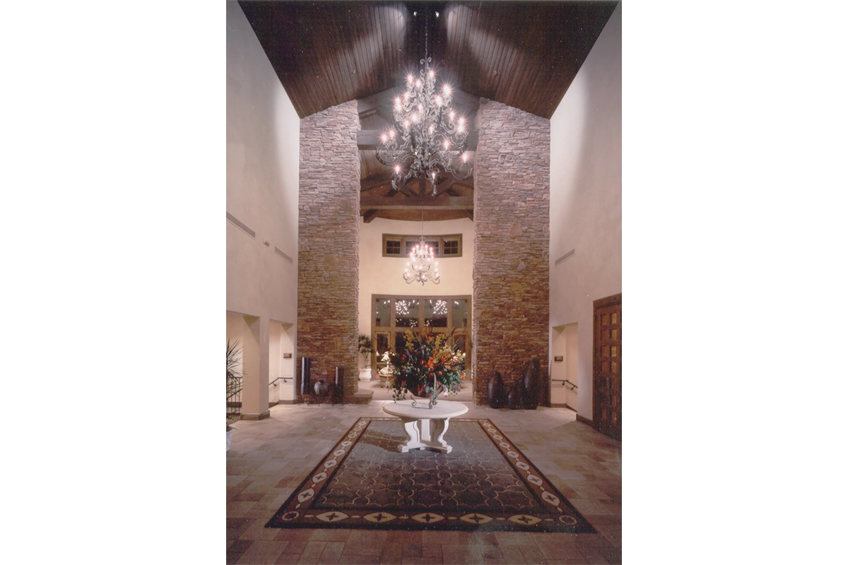 Fire Rock Country Club grand entrance foyer with soaring vaulted ceiling, crystal chandeliers, stacked stone walls, and elegant architectural details