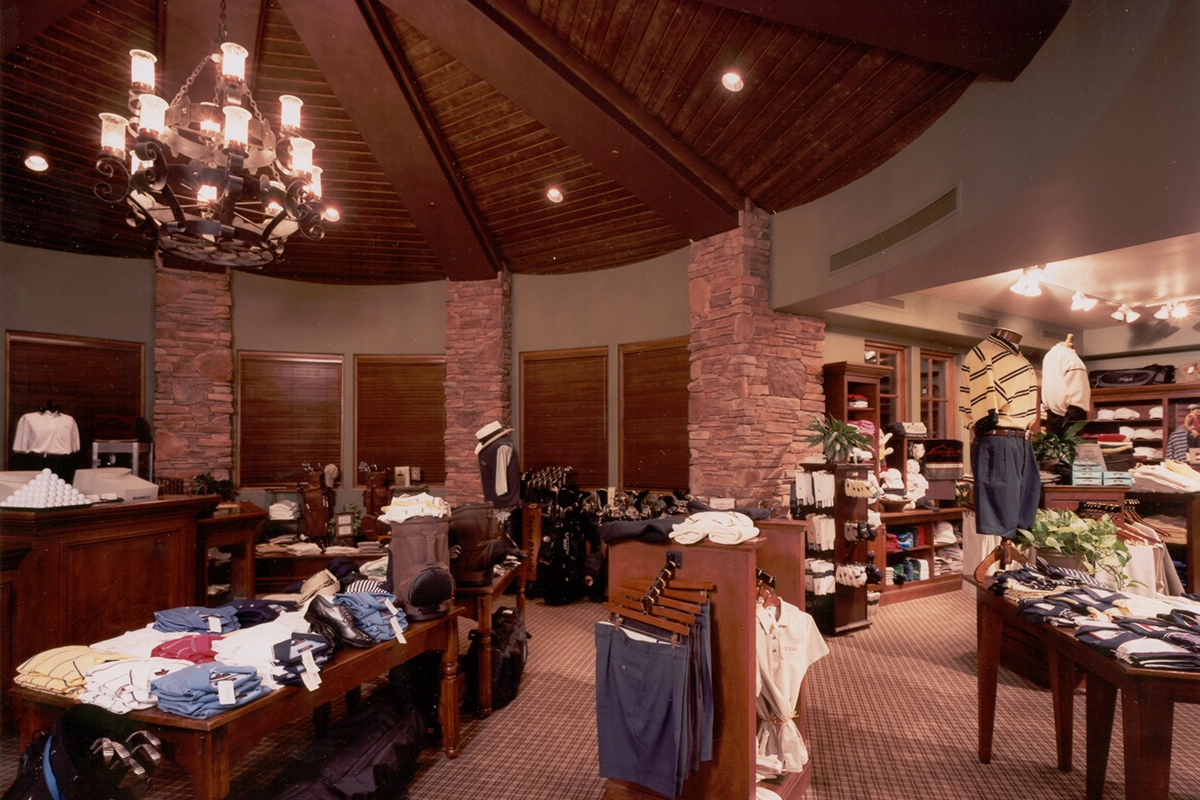 Fire Rock Country Club pro shop interior featuring vaulted wood ceiling, stone columns, and golf apparel retail display area