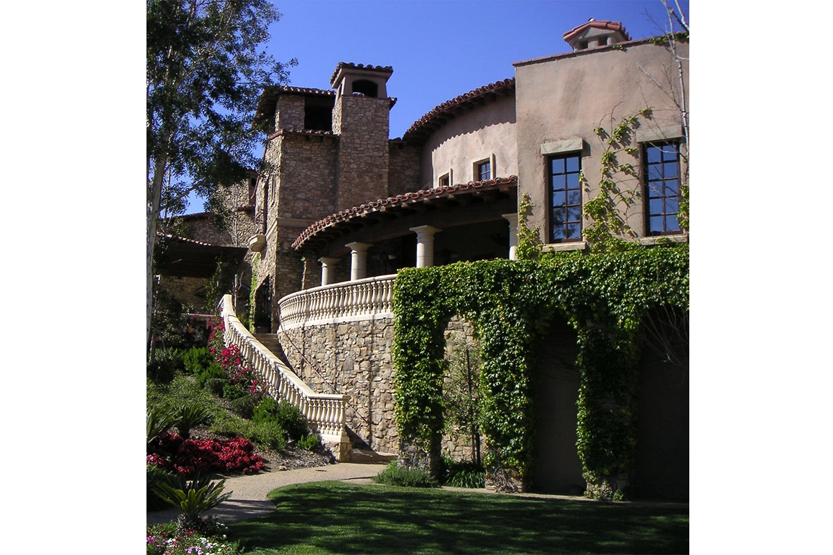 Elegant curved stone staircase with white balustrade at The Bridges at Rancho Santa Fe private club surrounded by lush gardens