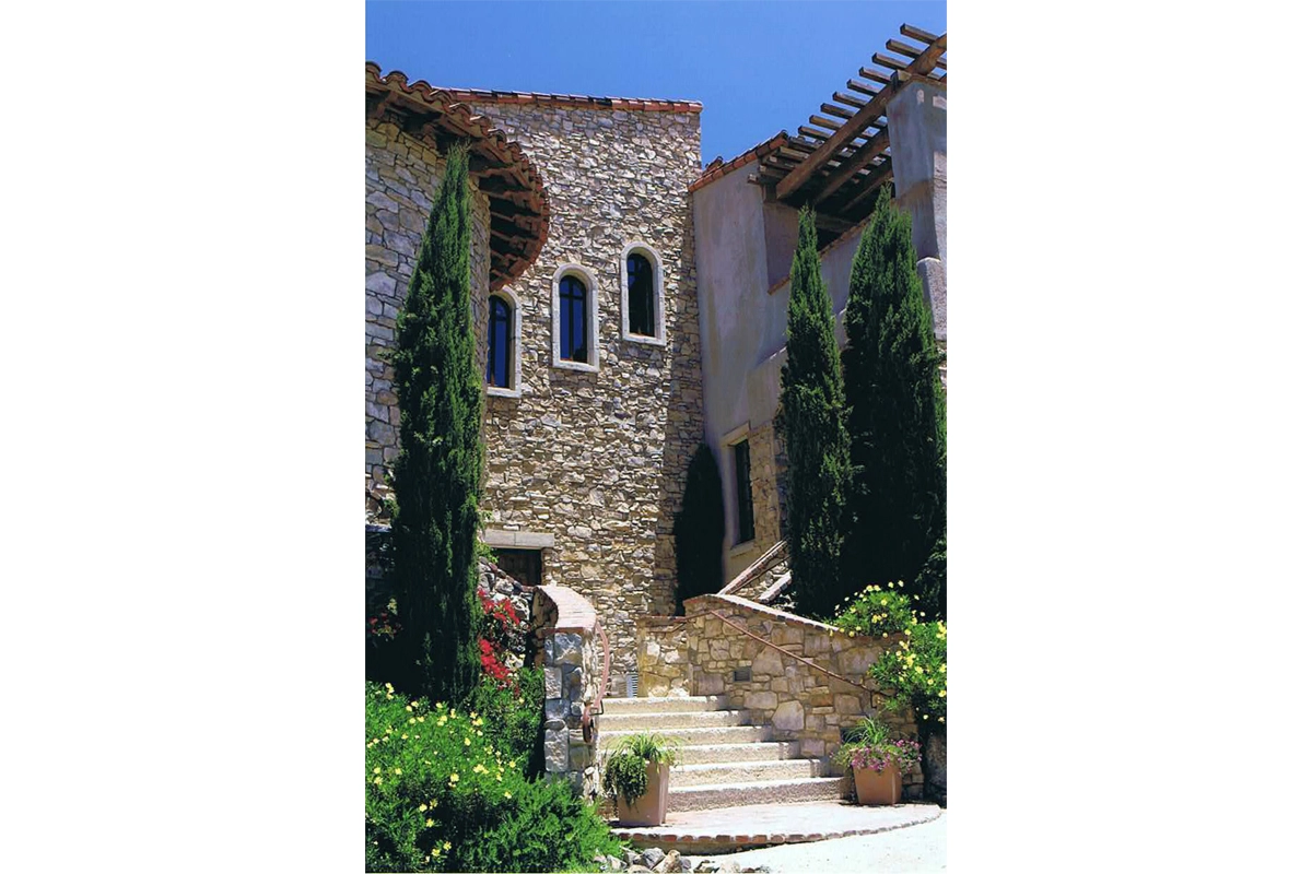 Mediterranean stone stairway leading to Bridges clubhouse at Rancho Santa Fe with Italian cypress trees and terra cotta tile roof